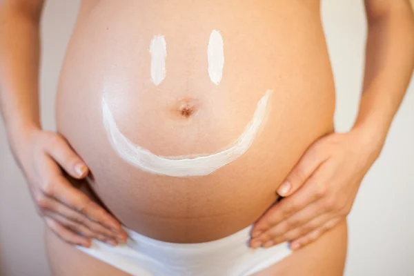 Mujer embarazada con una sonrisa en el estómago —  Fotos de Stock