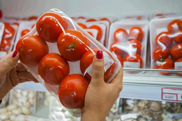 Tomate embalado com mão de mulher no supermercado — Fotografia de Stock