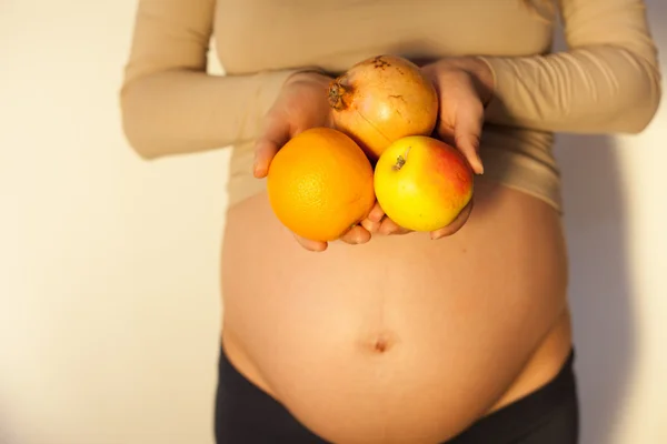 Mulher grávida segurando uma fruta — Fotografia de Stock