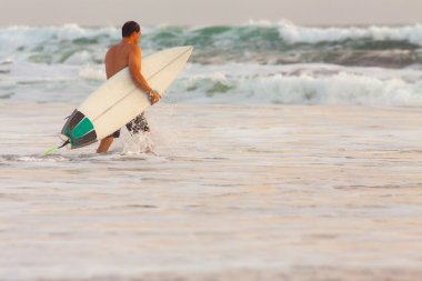 Sörfçü bir sahil şeridi üzerinde surfboard ile