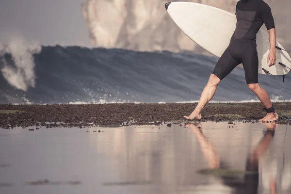 Surfer met surfboard op een kustlijn — Stockfoto