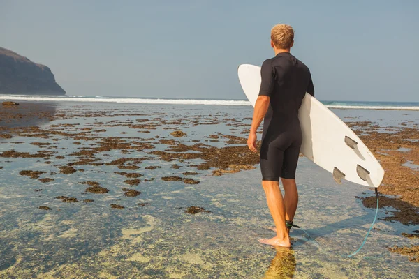 Surfista com prancha em um litoral — Fotografia de Stock