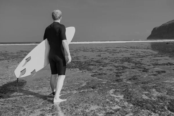 Surfista com prancha em um litoral — Fotografia de Stock