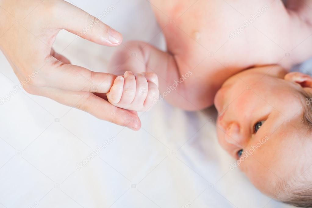Baby girl holding her mother's finger