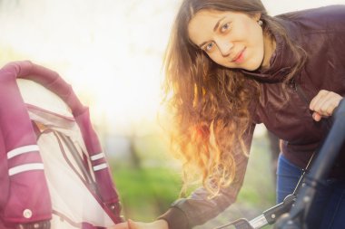 açık, mutlu anne bebek arabası sallıyor