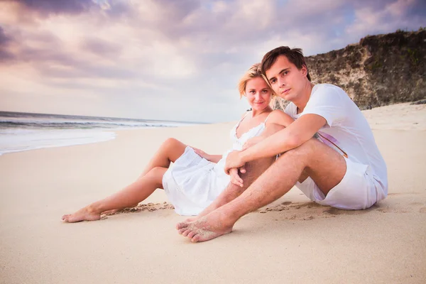 Boda hermosa pareja vestida de blanco sentado en la playa — Foto de Stock