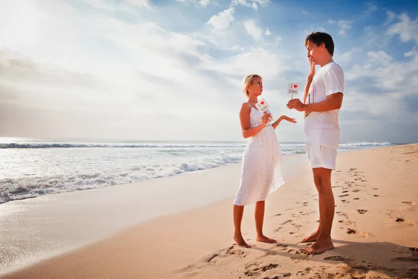 Beautiful couple on the beach are holding frame with signs of love and heart — Stock Photo, Image