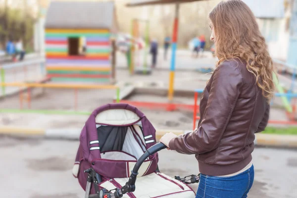 Mamma på utomhus skakar en barnvagn — Stockfoto
