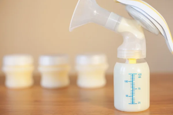 Manual breast pump and milk at background — Stock Photo, Image