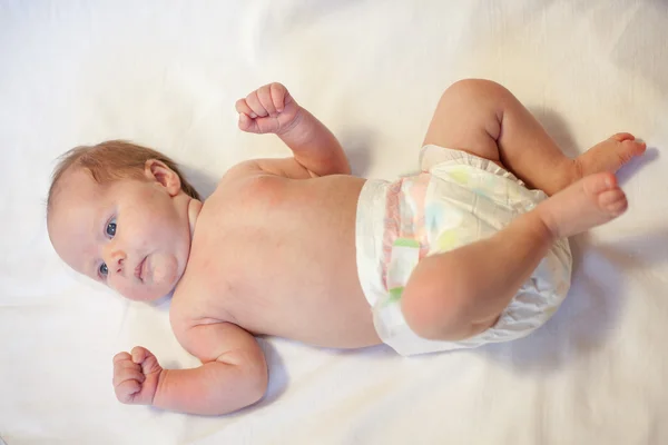 Newborn baby dressed in diaper, lying on a white background Stock Picture