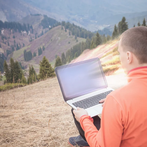 Homem usa laptop remotamente na montanha — Fotografia de Stock