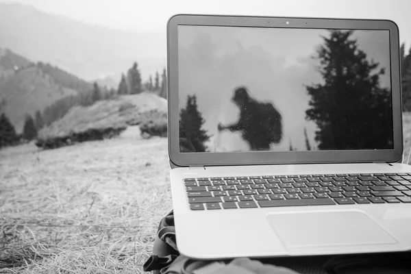 someone uses laptop remotely at mountain