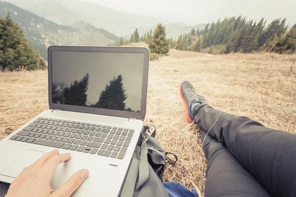 Tourist uses laptop remotely and relax at mountain — Zdjęcie stockowe