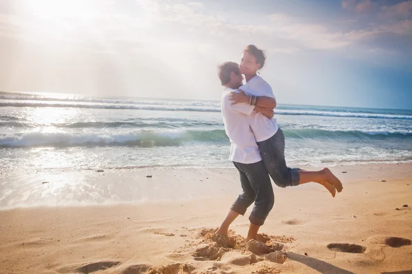 Glückliches Paar, das gerade geheiratet hat und am Strand hält — Stockfoto