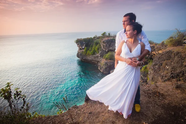 Traveling couple dressed at white at top of rock — Zdjęcie stockowe