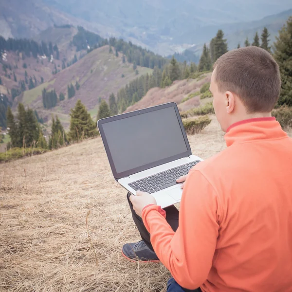 Homem usa laptop remotamente na montanha — Fotografia de Stock