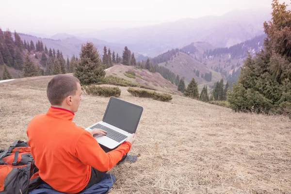 Man uses laptop remotely at mountain — Stock Photo, Image