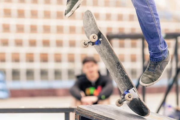 Teenager doing a trick by skateboard on a rail in skate park — Stock Fotó