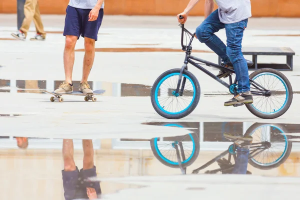 Handsome guys with skateboard and bicycle at freestyle park outdoors — 스톡 사진