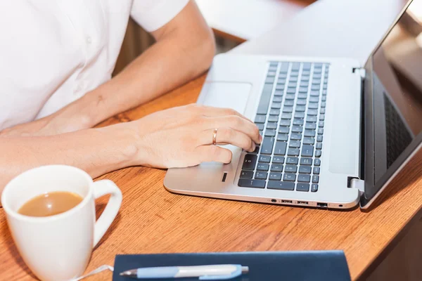 Joven utiliza el ordenador portátil en su lugar de trabajo —  Fotos de Stock