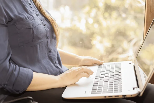 Beautiful happy student with a laptop sitting against bright window — Zdjęcie stockowe