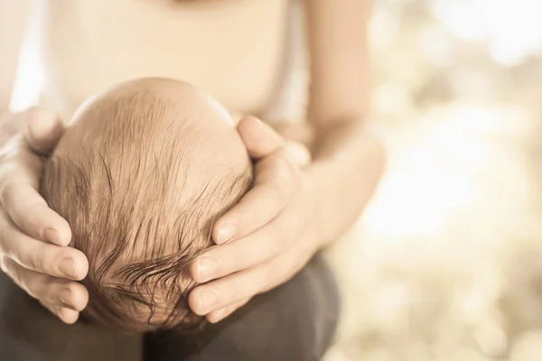 Mother holding baby head at hands — Stock Photo, Image