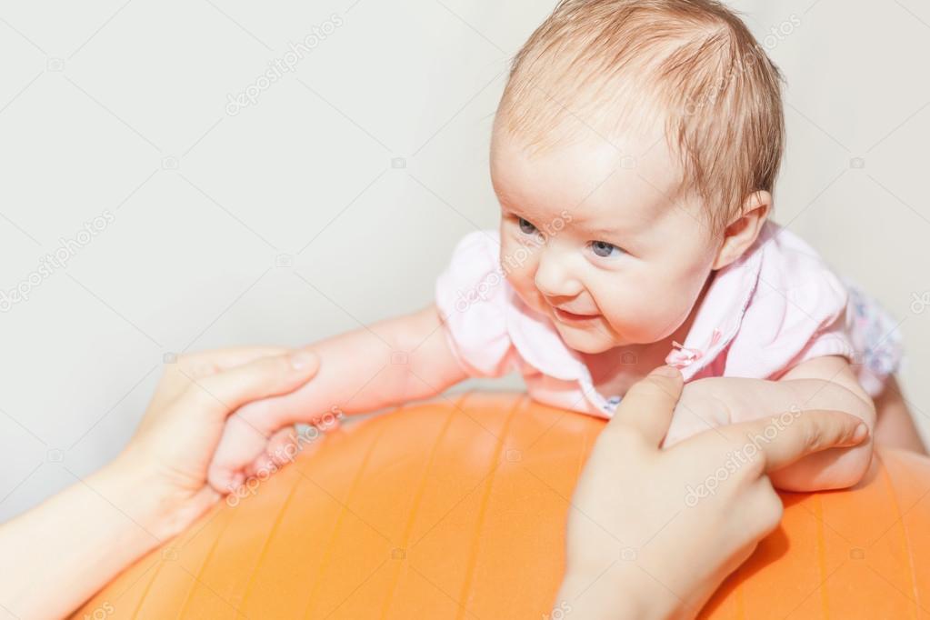 Mom with happy baby doing exercises at gymnastic ball