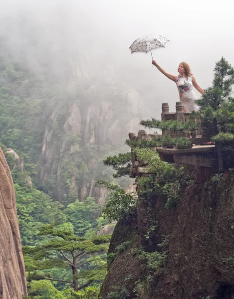 Young women with umbrella at cloudy weather on top of the Chinese mountain of Huangshan — Φωτογραφία Αρχείου