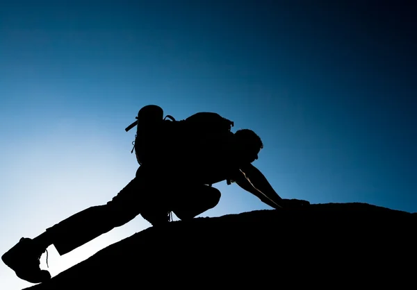 Silhouette of climbing young adult at the top of summit — Stock Photo, Image