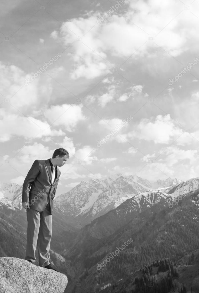 Young businessman looking down from the mountain top