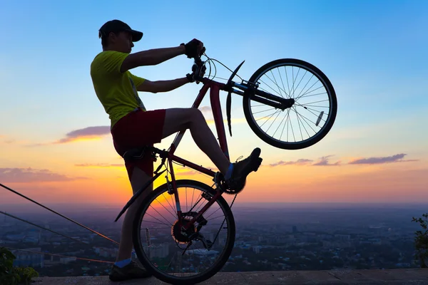 Egy fiatal férfi-egy biciklit, naplementekor. — Stock Fotó