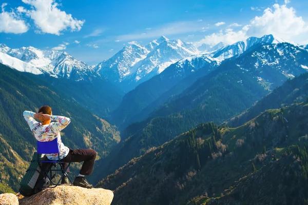 Чоловік розслабляється із задоволенням на вершині гори — стокове фото