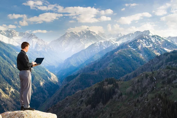 Joven hombre de negocios usando su portátil en la cima de la montaña — Foto de Stock