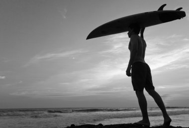 Adam sörfçü bir sahil şeridi üzerinde surfboard ile. Bali. Endonezya