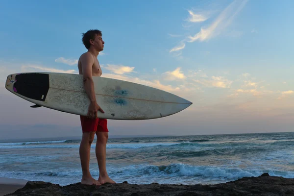 Hombre surfista con tabla de surf en una costa. ¡Bali! Países Bajos —  Fotos de Stock