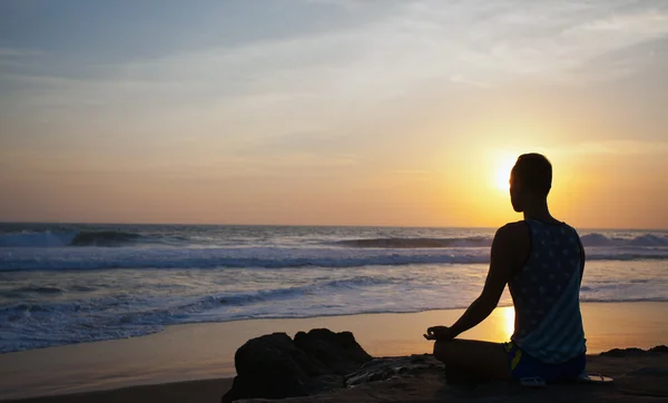 Uomo seduto che fa yoga sulla riva dell'oceano — Foto Stock