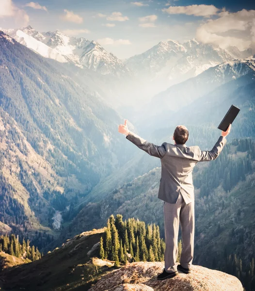 El hombre de negocios con portátil en la cima de la montaña es por favor —  Fotos de Stock