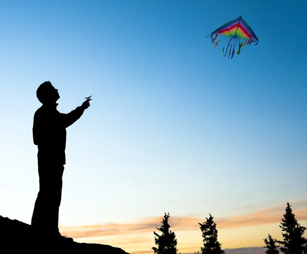 Giovane uomo isolato volare un aquilone arcobaleno — Foto Stock