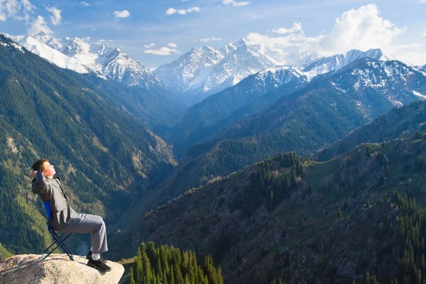 The businessman at the top of the mountain is pleased with the a — Stock Photo, Image