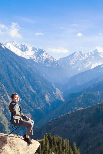 The businessman at the top of the mountain is talking about new — Stock Photo, Image