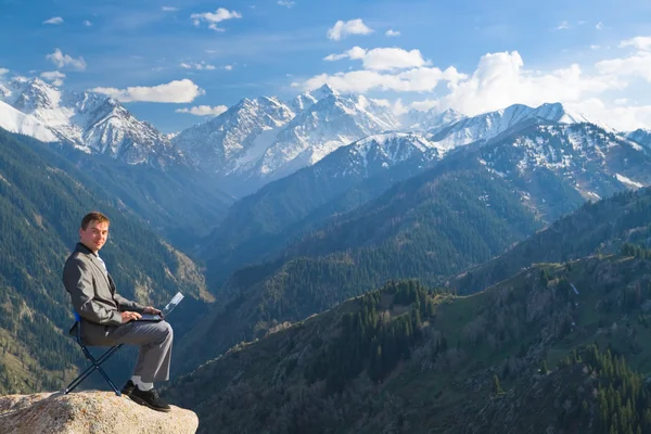 Бизнесмен на вершине горы использует свой ноутбук — стоковое фото