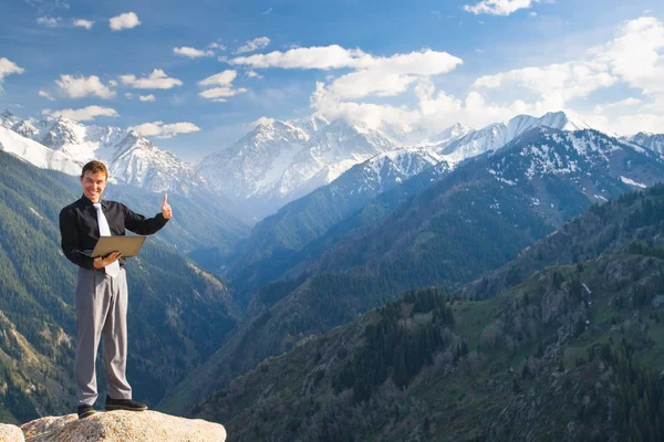 Joven hombre de negocios con una amplia sonrisa en la cima de la montaña — Foto de Stock