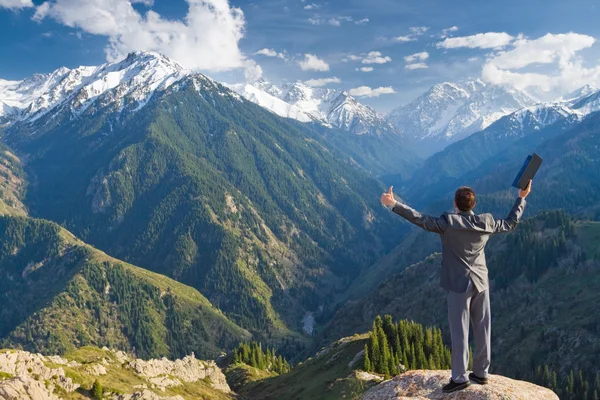 El hombre de negocios con portátil en la cima de la montaña es por favor — Foto de Stock