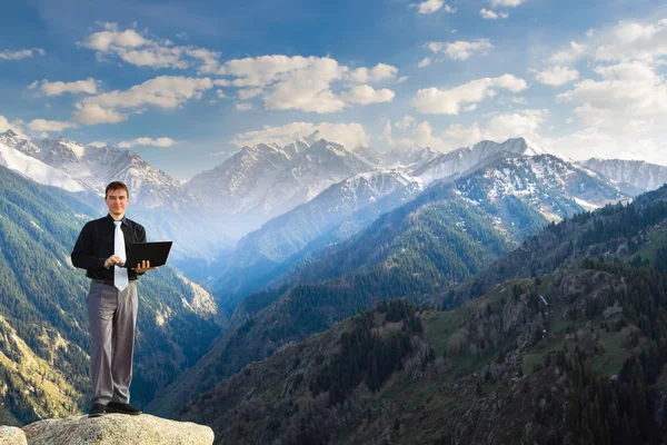 Joven hombre de negocios usando su portátil en la cima de la montaña — Foto de Stock