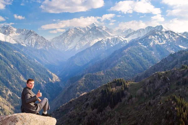 The businessman at the top of the mountain is pleased with the a — Stock Photo, Image