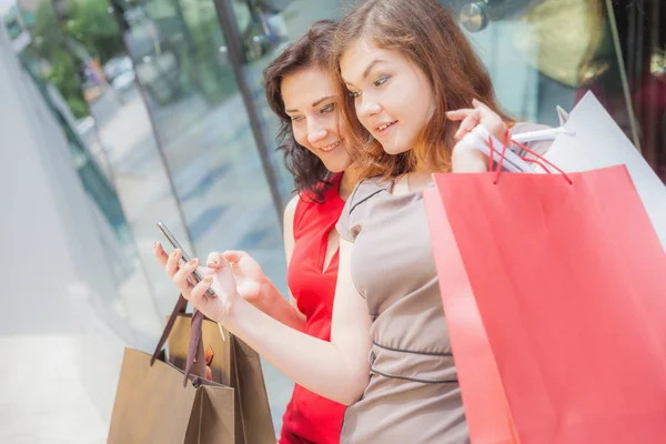 Happy fashion women with bags using mobile phone, shopping center — 图库照片