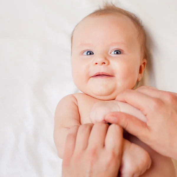 Mother makes baby massage with happy newborn at white bed — Stock Photo, Image