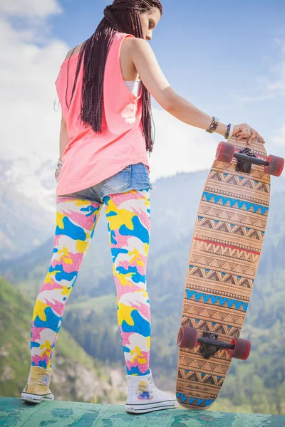 Hippie young and beautiful girl with longboard skateboard at mountain — ストック写真