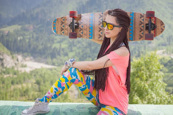 Hippie young and beautiful girl with longboard skateboard at mountain — ストック写真