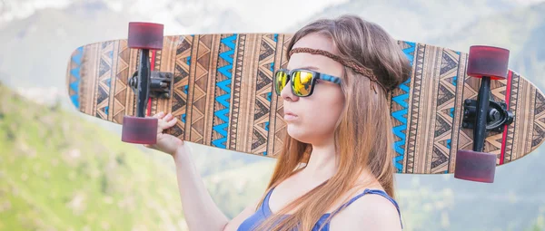 Hippie young and beautiful girl with longboard skateboard at mountain — ストック写真